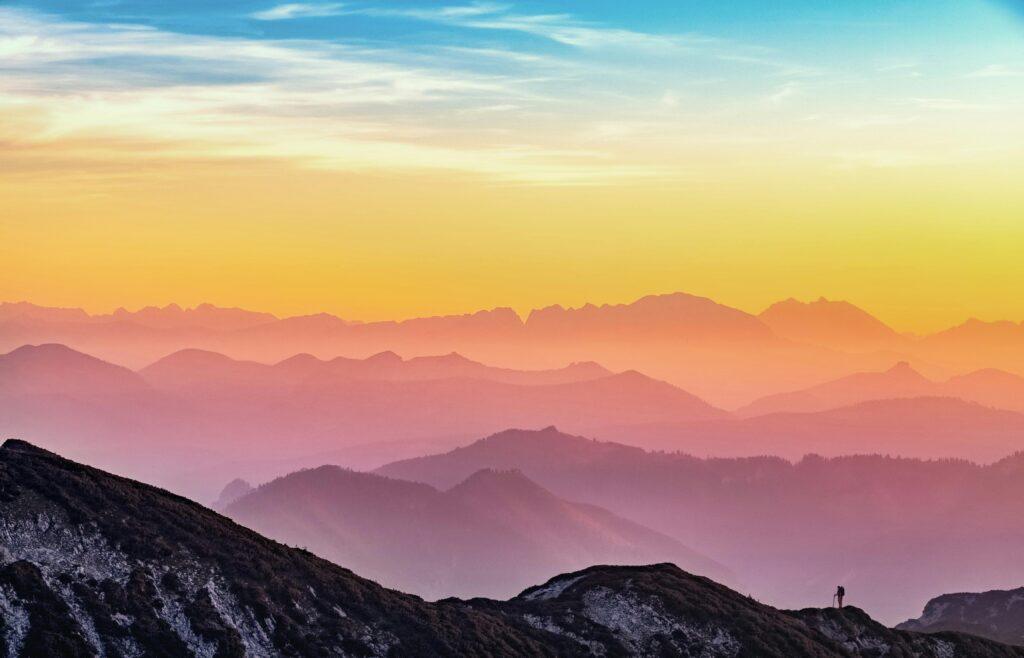pexels-photo-1323550-1323550 Colorful sunrise over misty mountains in Altmünster, Austria with a lone hiker silhouette.